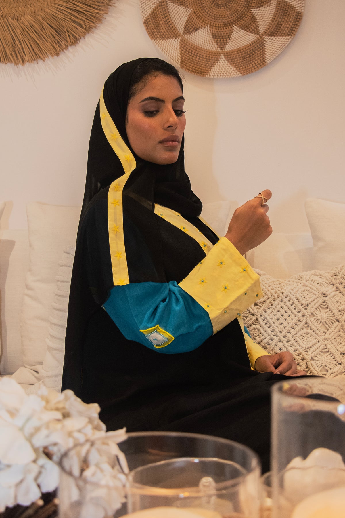Woman wearing the PEONISA Daylight black abaya with blue and yellow sleeve details.
