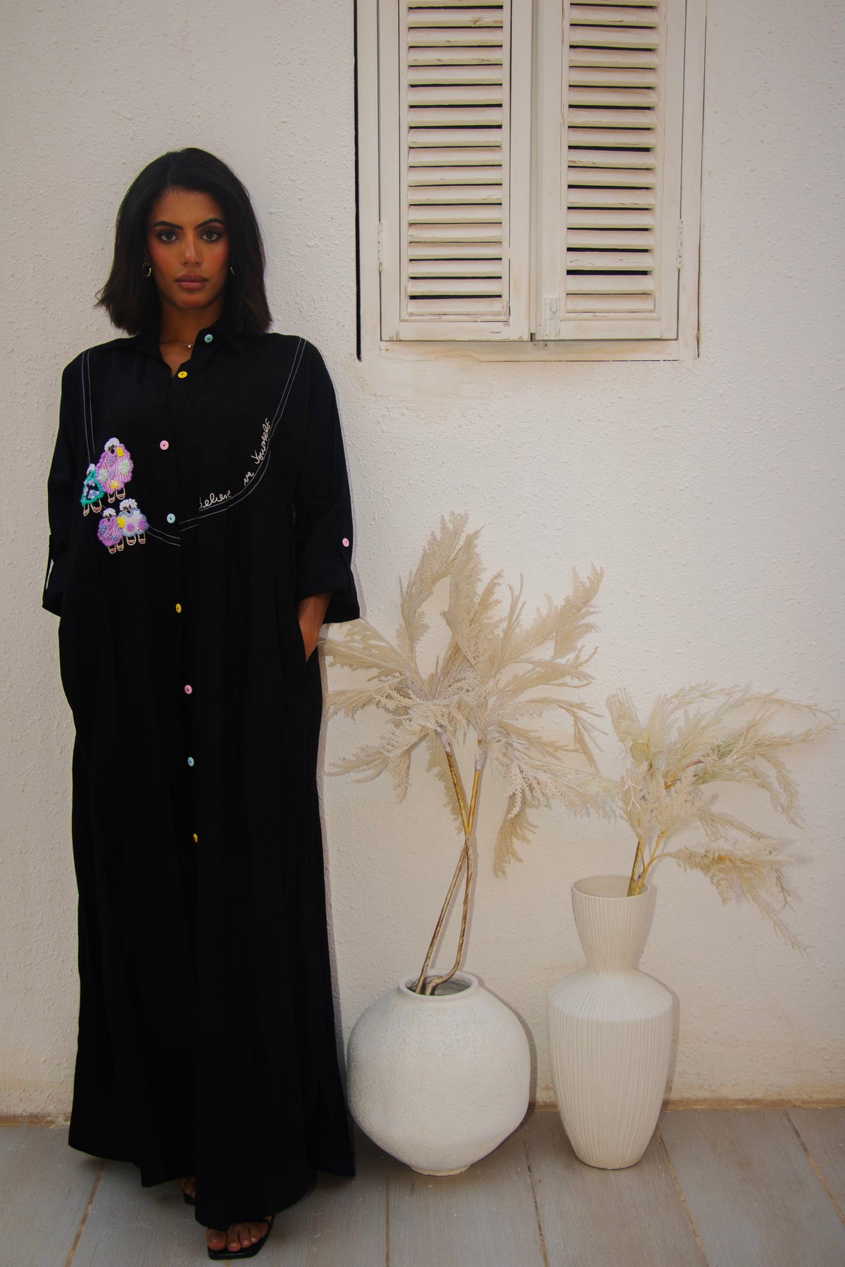 Front view of PEONISA Rifq black abaya with colorful embroidered motifs and multicolor button accents.