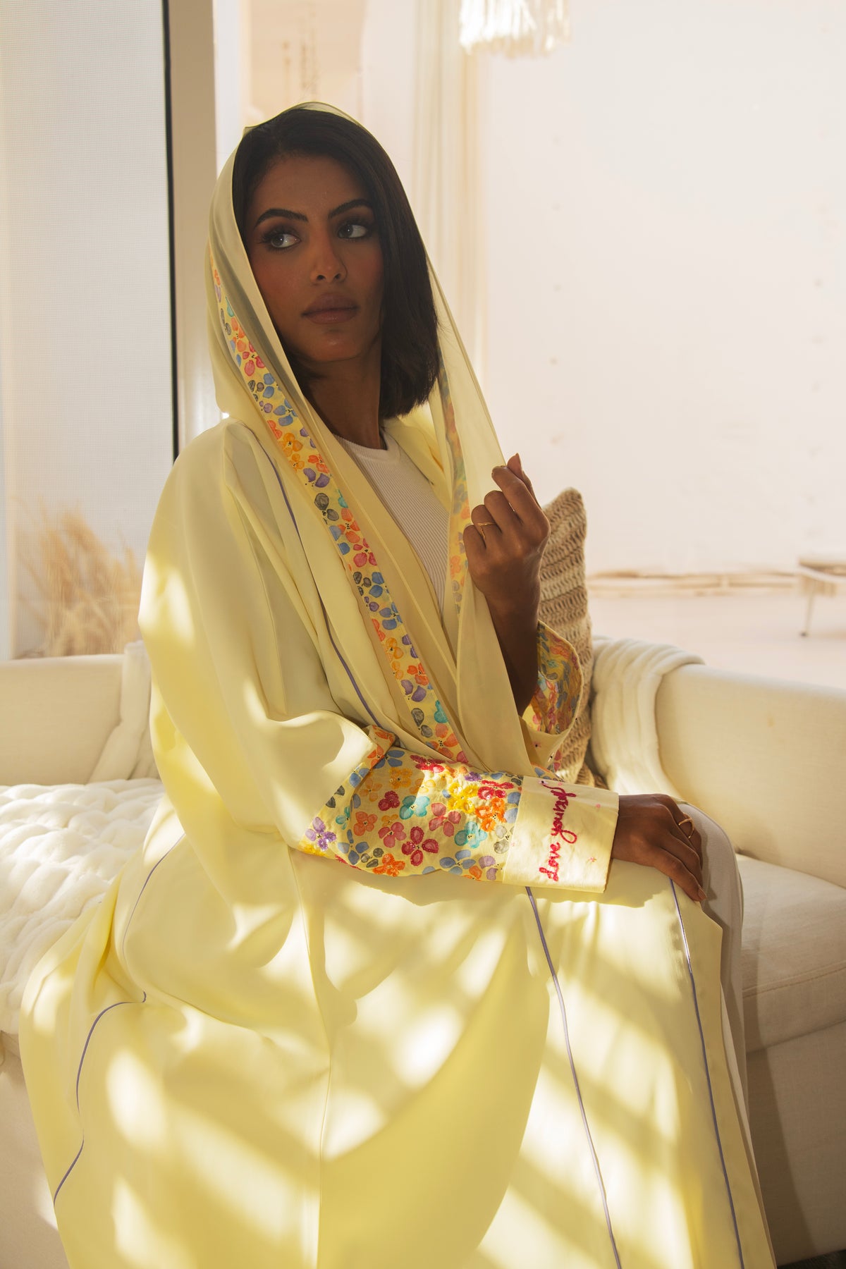 Close-up of PEONISA Soleil pale yellow abaya showing multicolor floral cuff detail and patterned front trim.